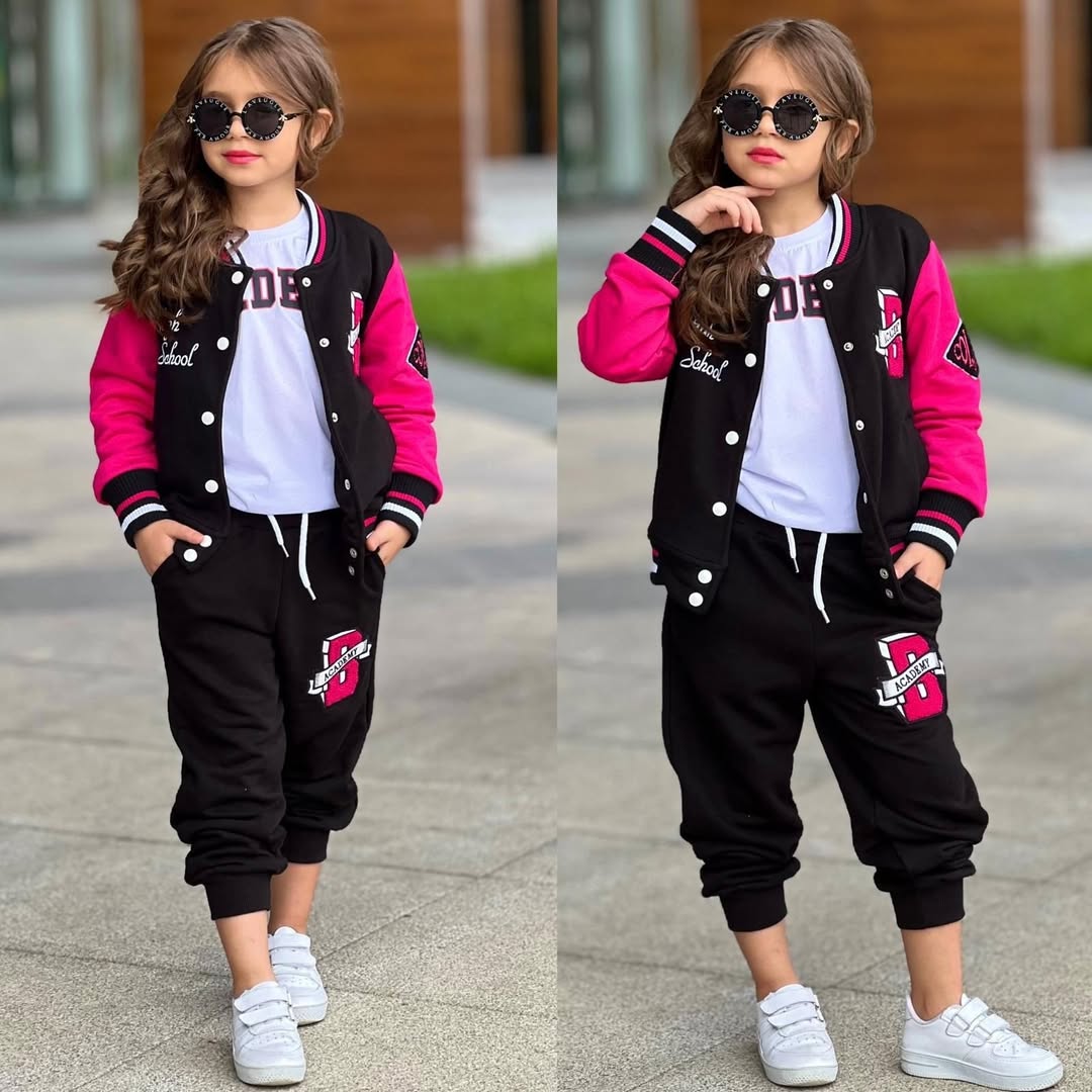 Full-body view of a child wearing a black-and-pink varsity-style outfit and sunglasses, shown in two side-by-side poses outdoors in soft daylight.