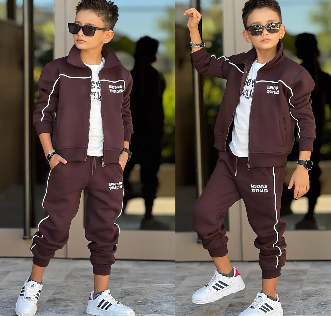 Two full-body views of a child wearing a burgundy tracksuit, white sneakers and sunglasses, posed in front of glass doors with bright outdoor lighting.